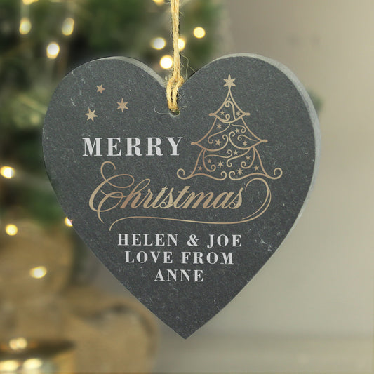 Personalised Heart-shaped Christmas ornament with 'Merry Christmas' text and tree design, against a blurred festive background.