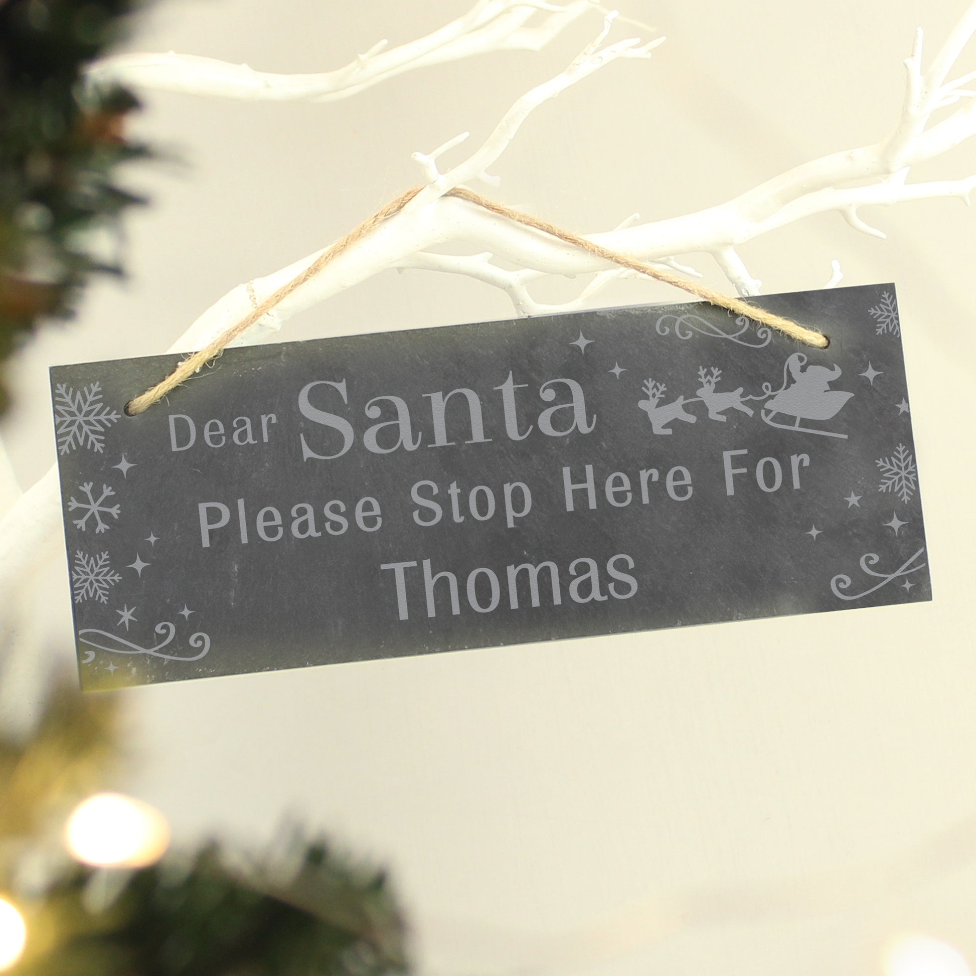 Decorative sign for Christmas with 'Dear Santa Please Stop Here For Thomas' text, hanging on a branch.