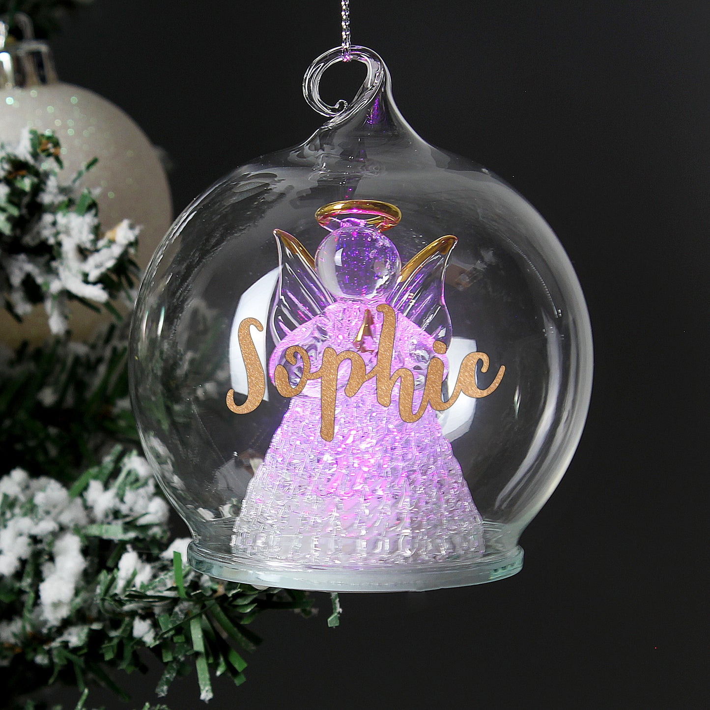 Decorative angel ornament with 'Sophie' in a glass sphere, Christmas tree in the background