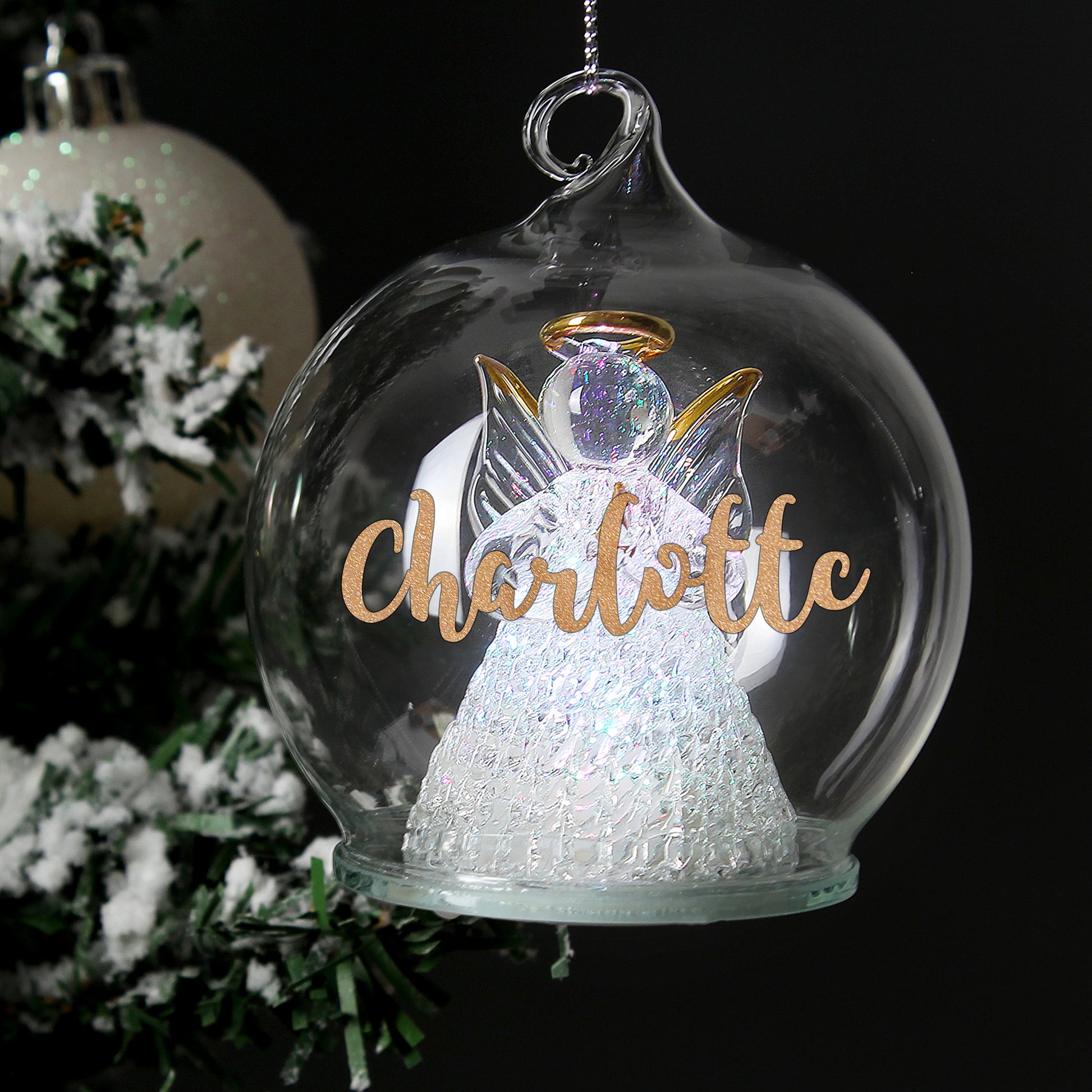 Personalised Decorative angel ornament with 'Charlotte' text inside a glass ball, Christmas tree in the background.