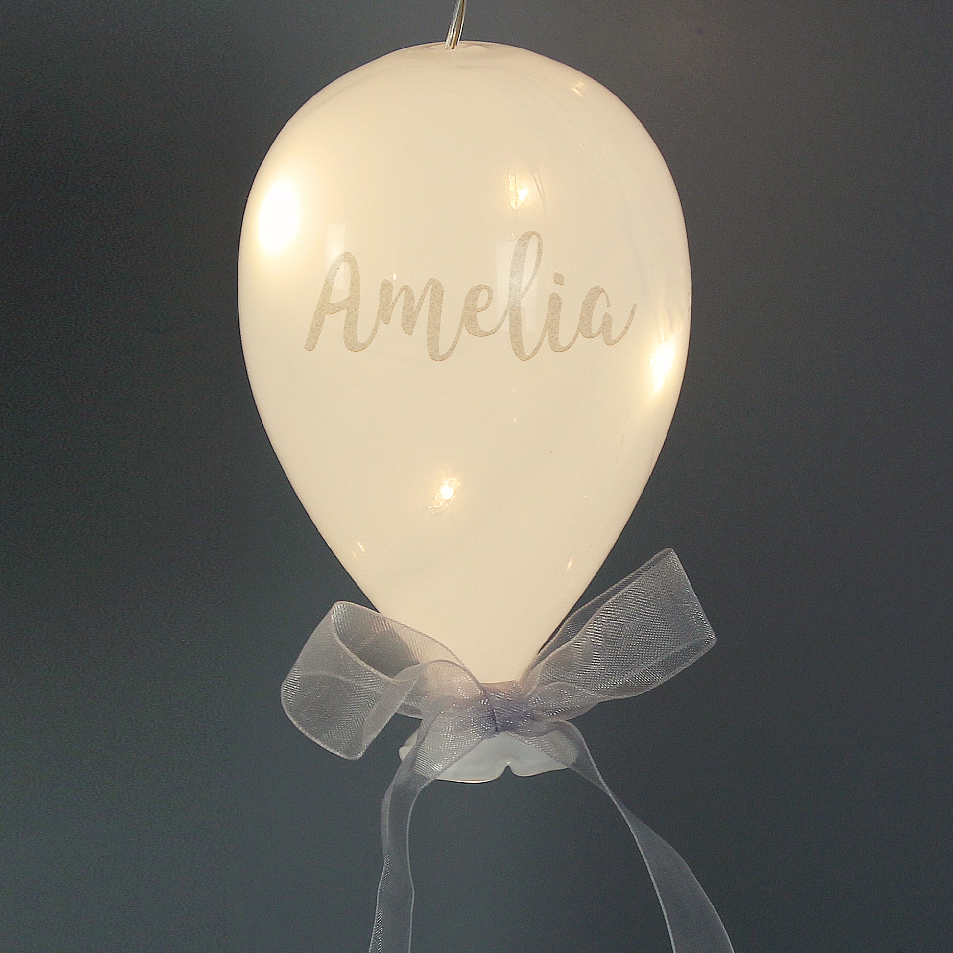 Decorative balloon with 'Amelia' written on it, featuring a bow against a dark background