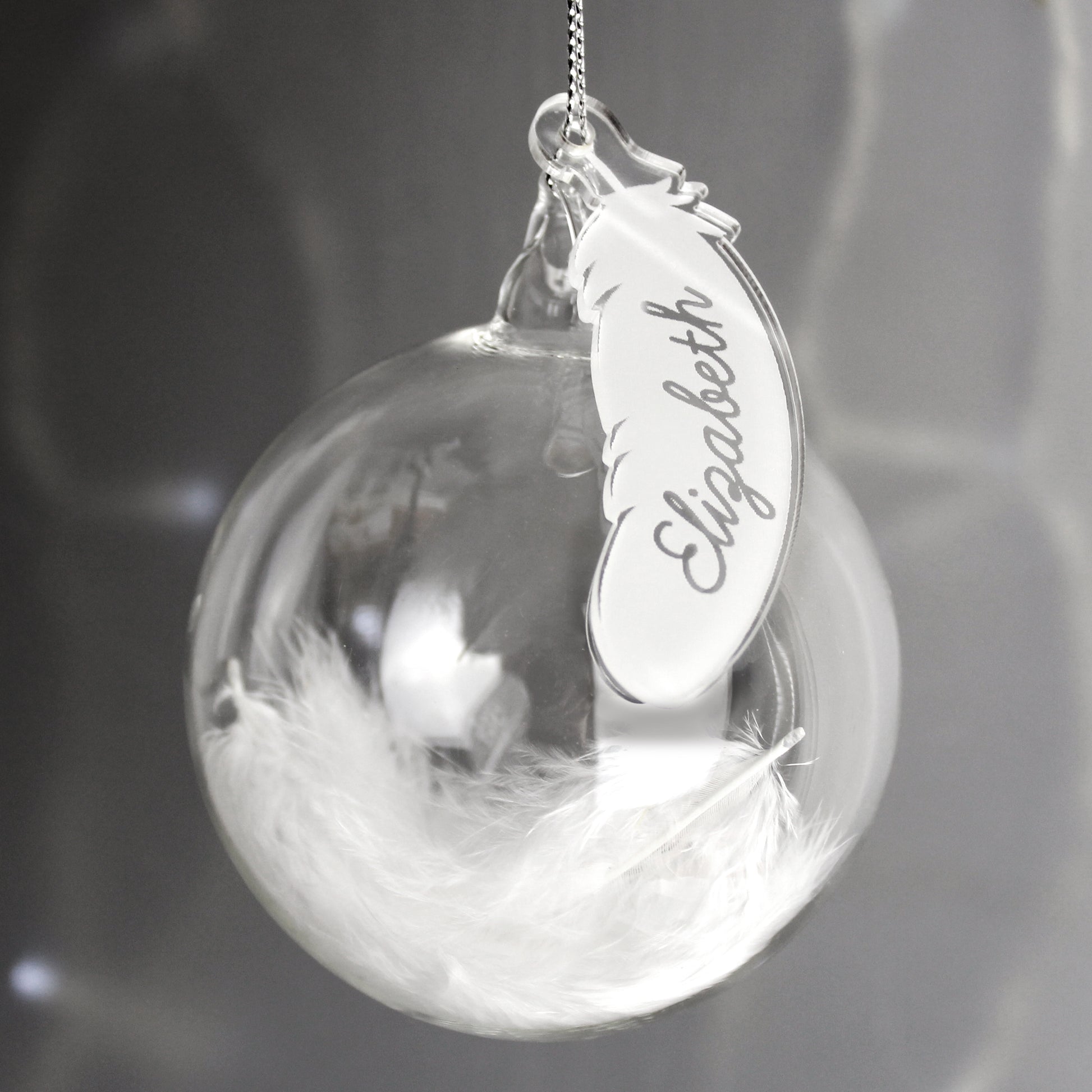Decorative ornament with feather and engraved name tag on a blurred background
