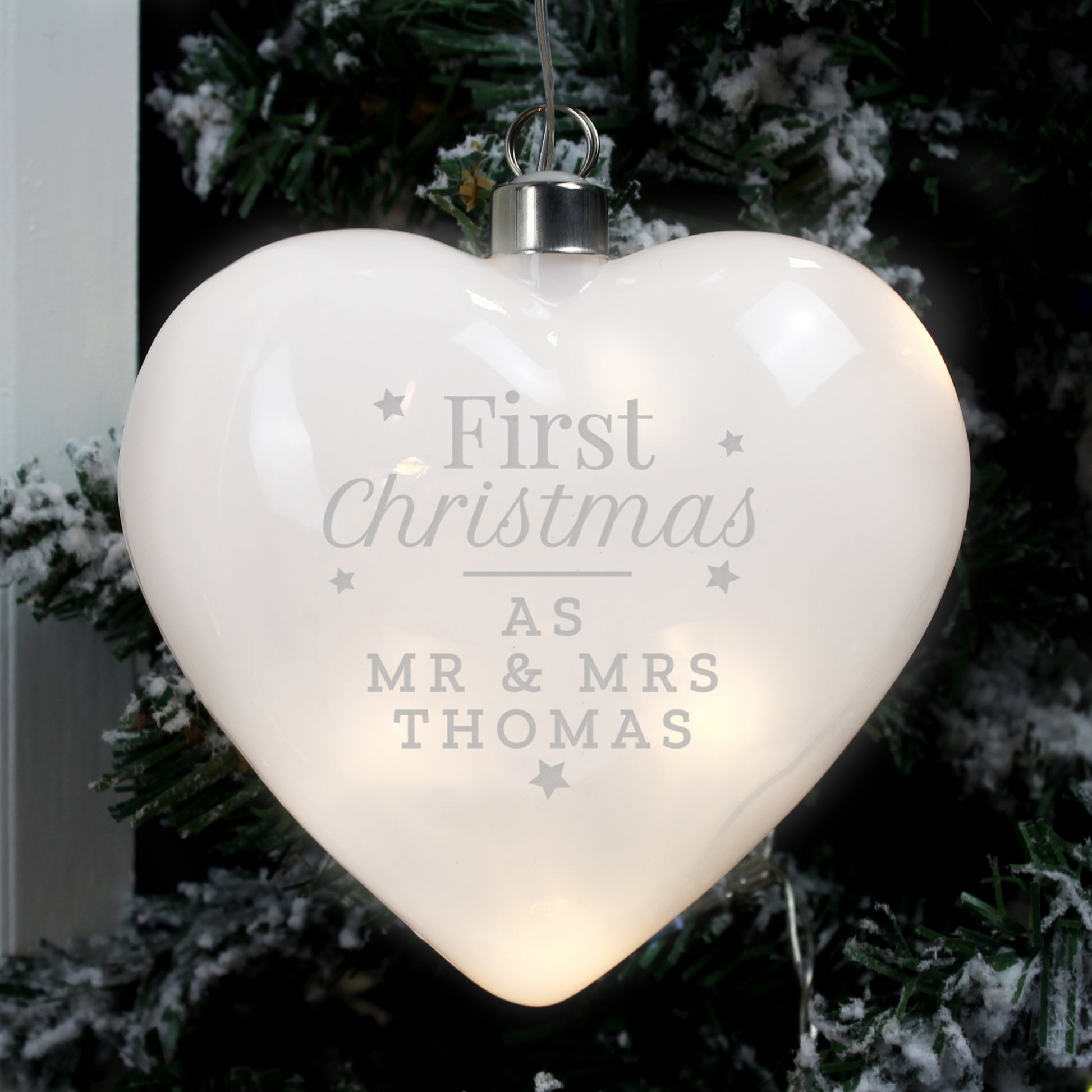 Heart-shaped LED ornament with 'First Christmas as Mr & Mrs Thomas' text, hanging on a tree.