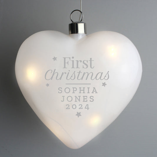 Heart-shaped ornament with 'First Christmas' engraving on a gray background