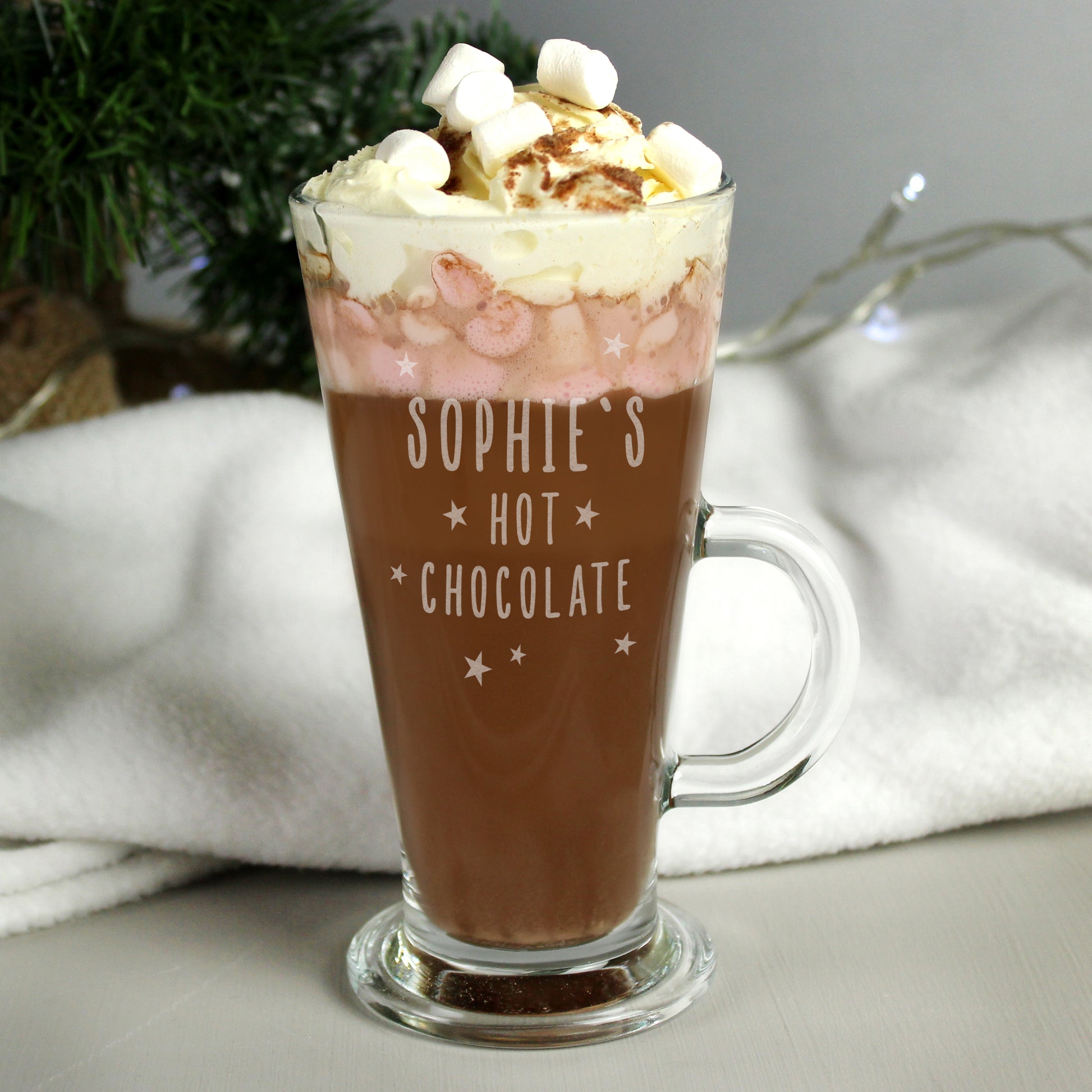 Glass mug of hot chocolate with whipped cream and marshmallows, labeled 'Sophie's Hot Chocolate', on a light background.