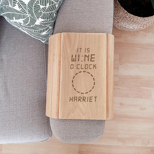 Personalised Wooden sofa tray with 'It is wine o'clock Harriet' text on a grey sofa.