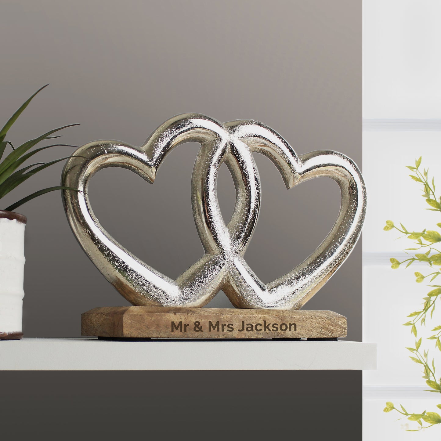 Decorative sculpture of two interlocking hearts on a wooden base with 'Mr & Mrs Jackson' engraving, against a neutral background.