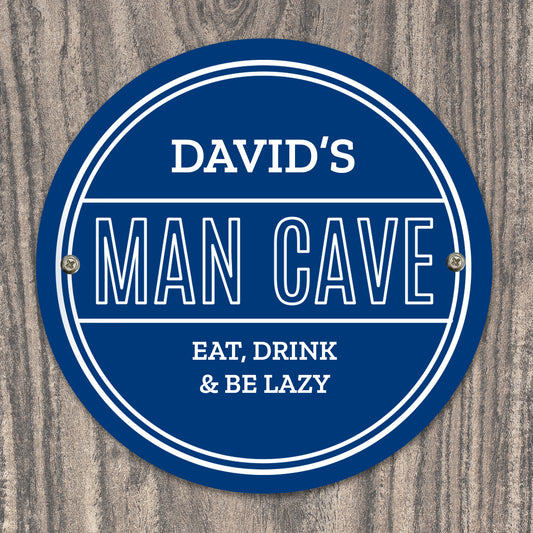 Personalised Circular blue sign with 'DAVID'S MAN CAVE EAT, DRINK & BE LAZY' text on a wooden background