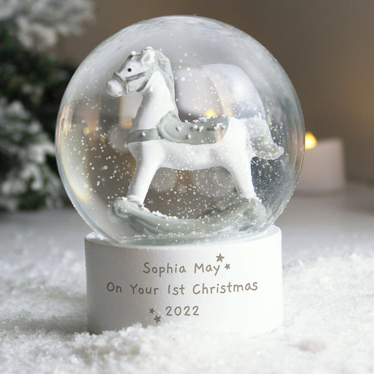 Personalised snow globe with rocking horse on a snowy base, featuring the text 'Sophia May On Your 1st Christmas 2022'.