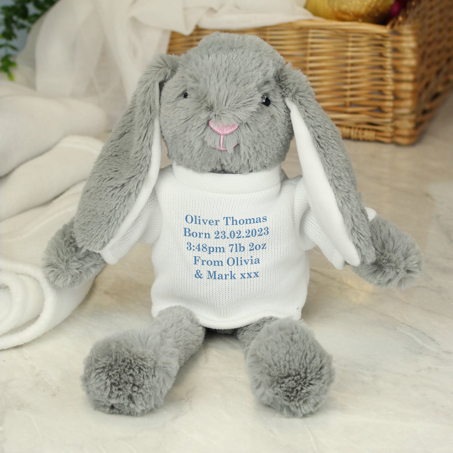 Grey plush bunny with embroidered text on a white blanket