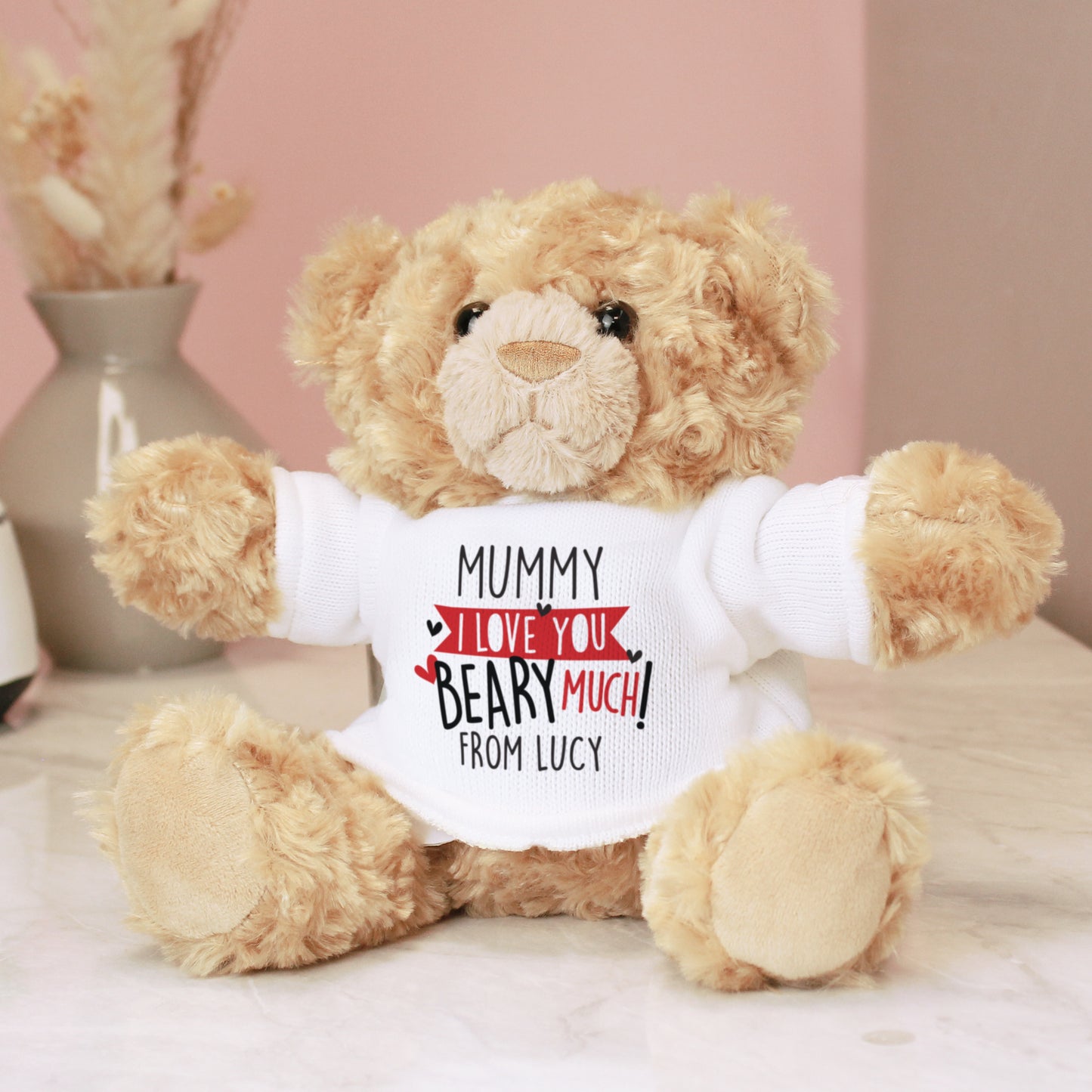 Teddy bear wearing a shirt with a personalised message on a light pink background
