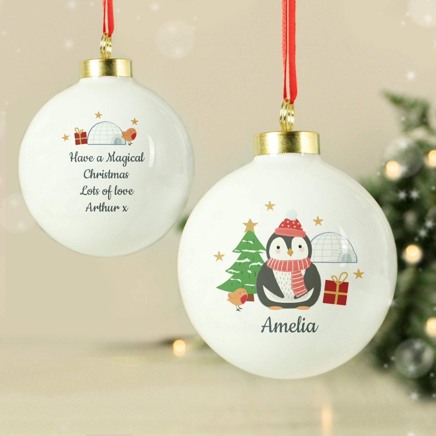 Two Christmas ornaments with penguin design and personalised text, hanging against a festive background.