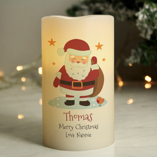 Decorative candle with Santa Claus illustration and personalised text, set against a blurred festive background.
