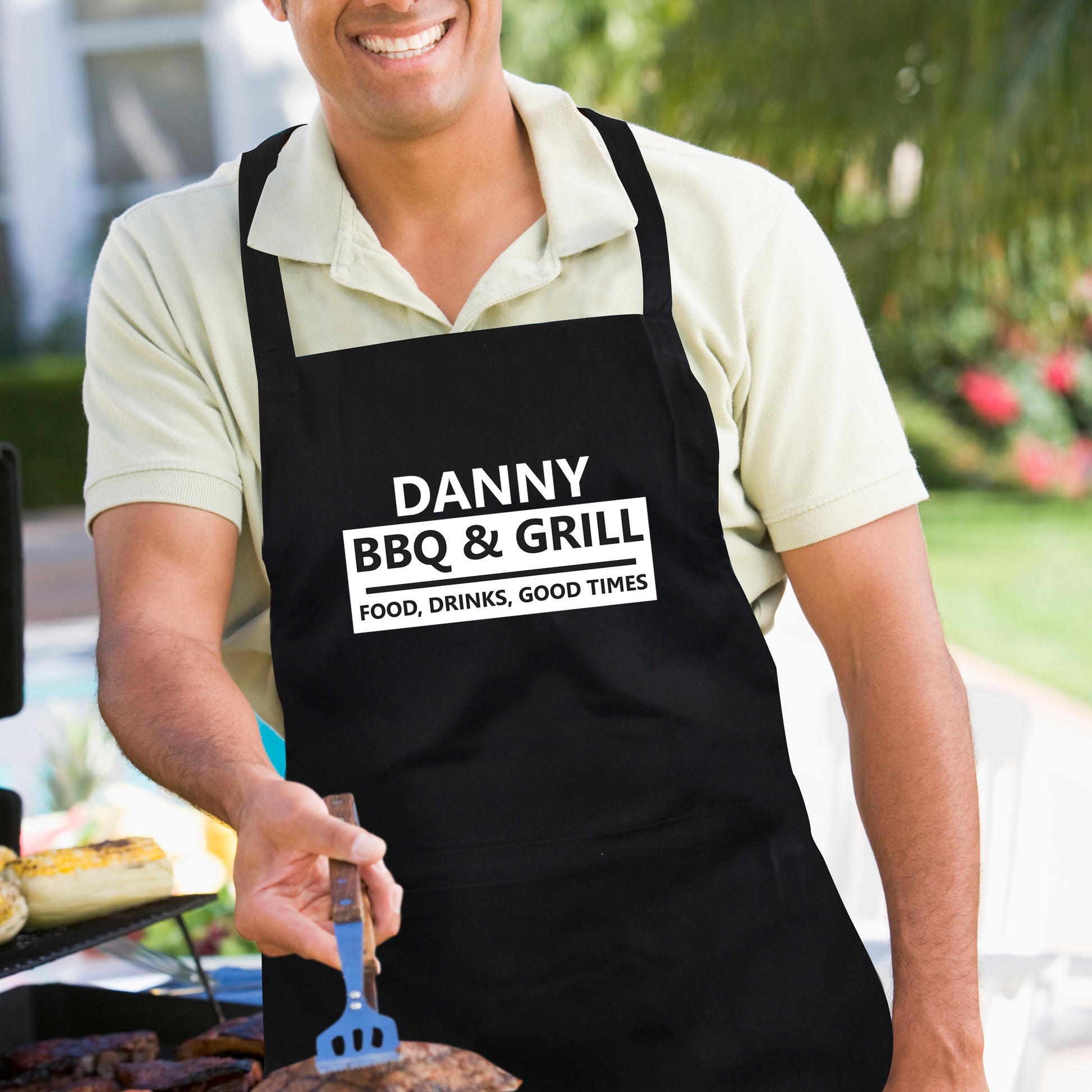 Man wearing a black apron with 'Danny BBQ & Grill' text, grilling outdoors.