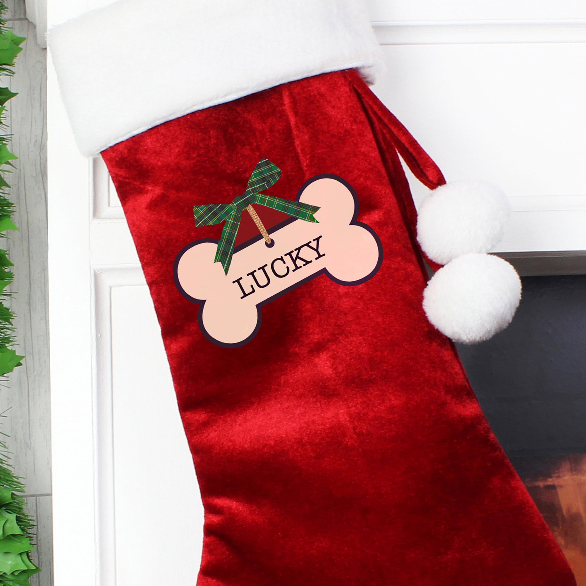 Red Christmas stocking with a bone-shaped patch and 'LUCKY' text, hanging on a white door.