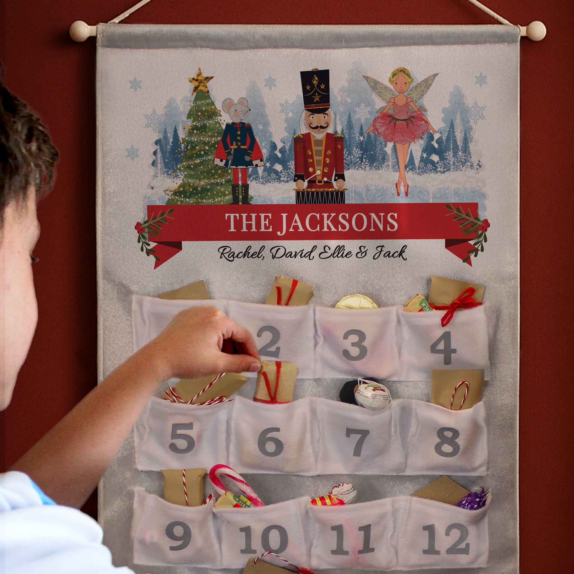 Advent calendar with personalized name 'The Jacksons' and festive illustrations on a red wall.