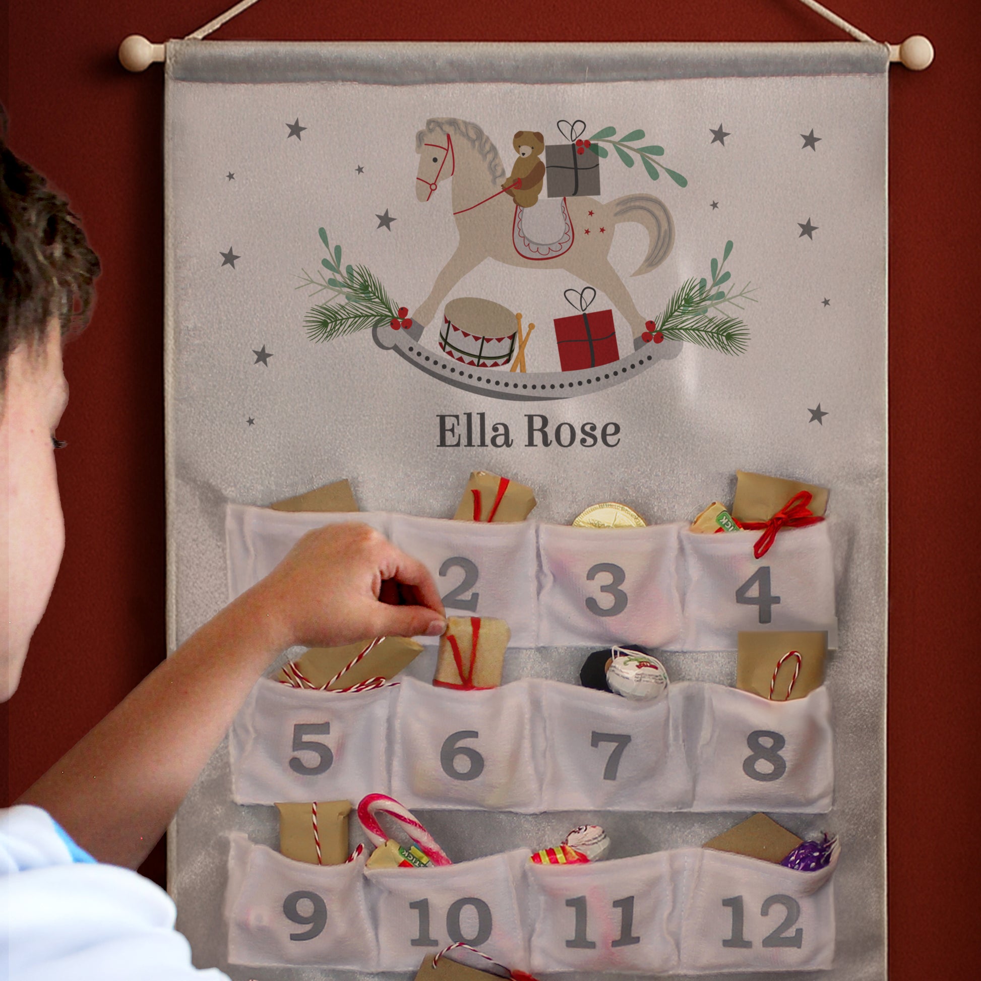 Advent calendar with a horse design and numbered pockets, being interacted with by a child.
