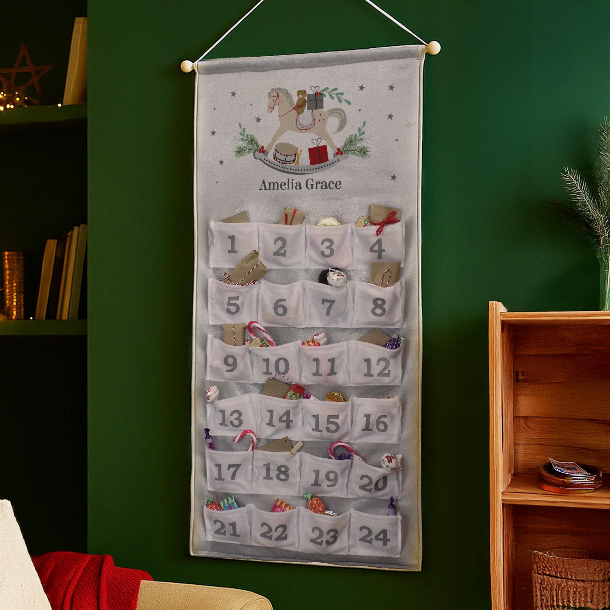 Hanging Advent calendar with decorative elements on a green wall.