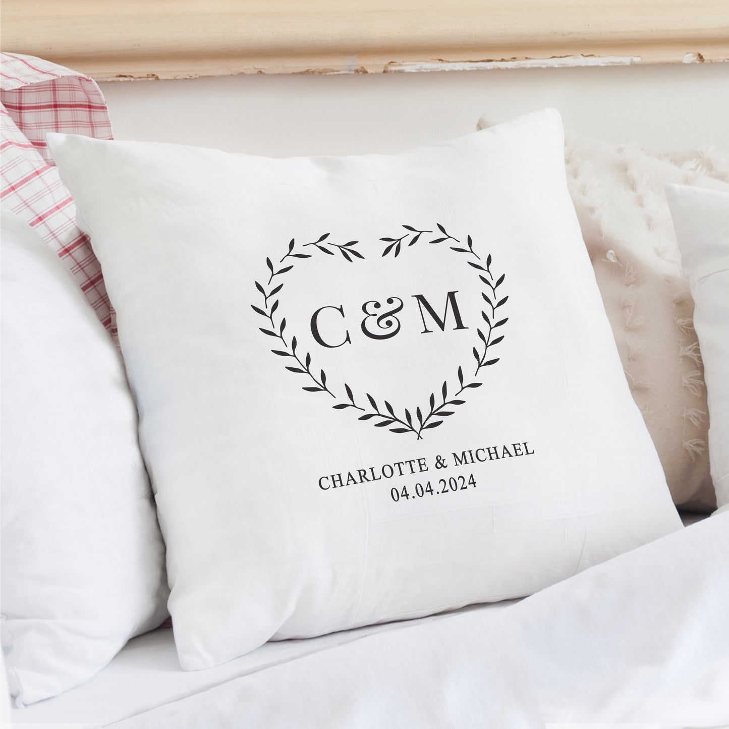 White pillow with monogram 'C&M' and text on a bed