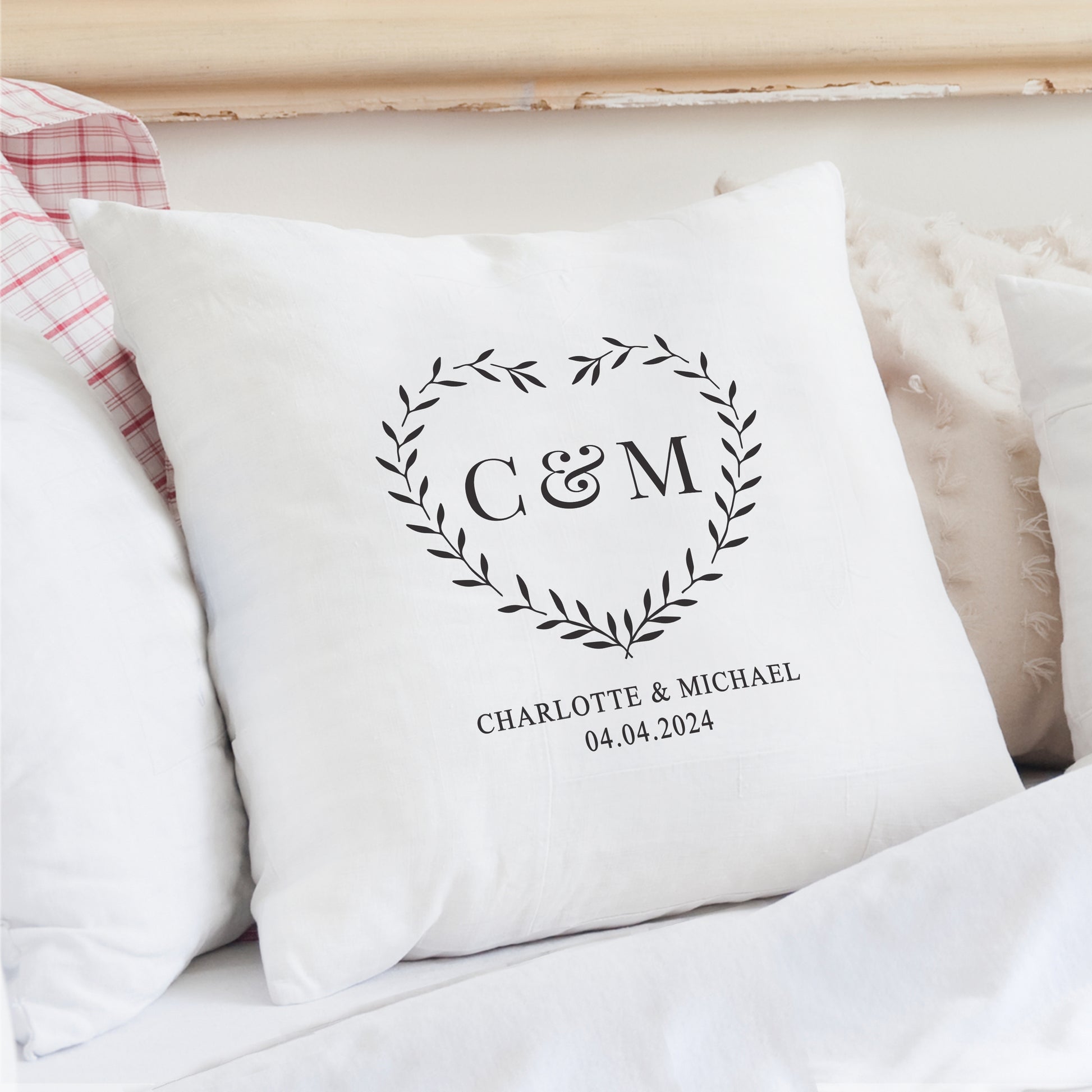 White pillow with monogram 'C&M' and text on a bed