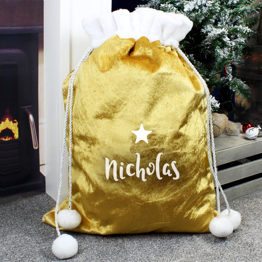 Gold drawstring bag with 'Nicholas' and a star, placed in front of a fireplace and Christmas tree.