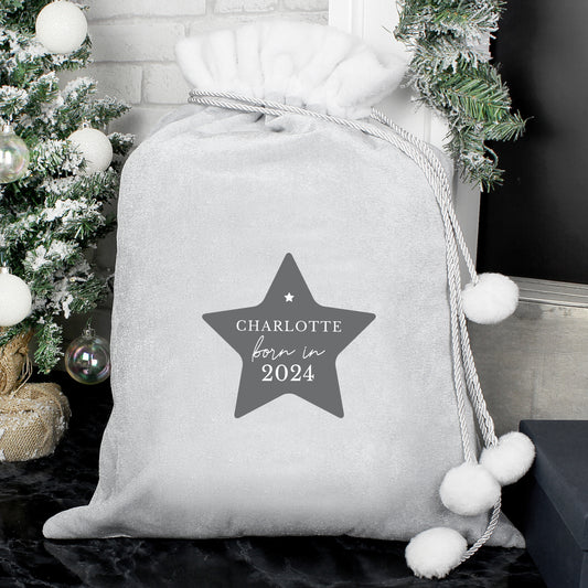 Gray gift bag with a star-shaped label reading 'Charlotte born in 2024' against a festive background.