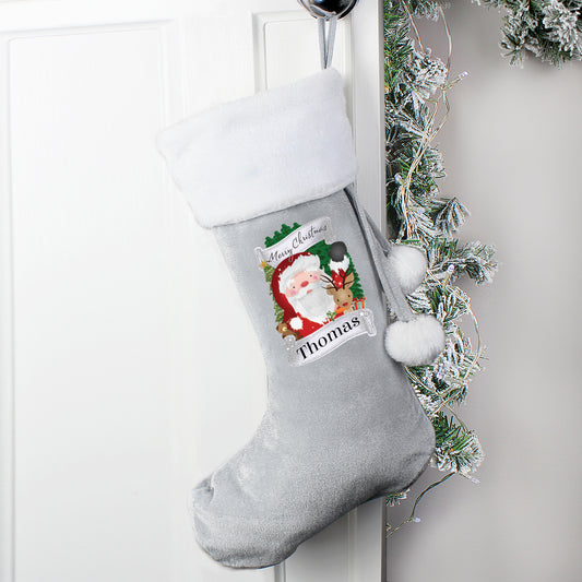 Grey Christmas stocking with Santa Claus design and 'Thomas' name tag, hanging on a white door with greenery.