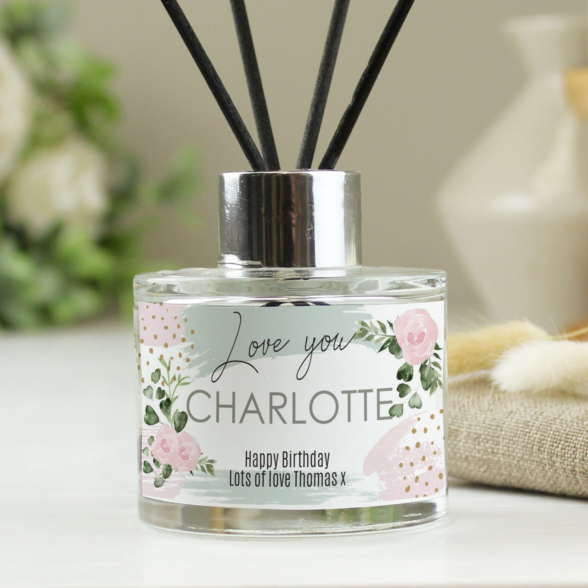 Reed diffuser with personalised floral label on a neutral background
