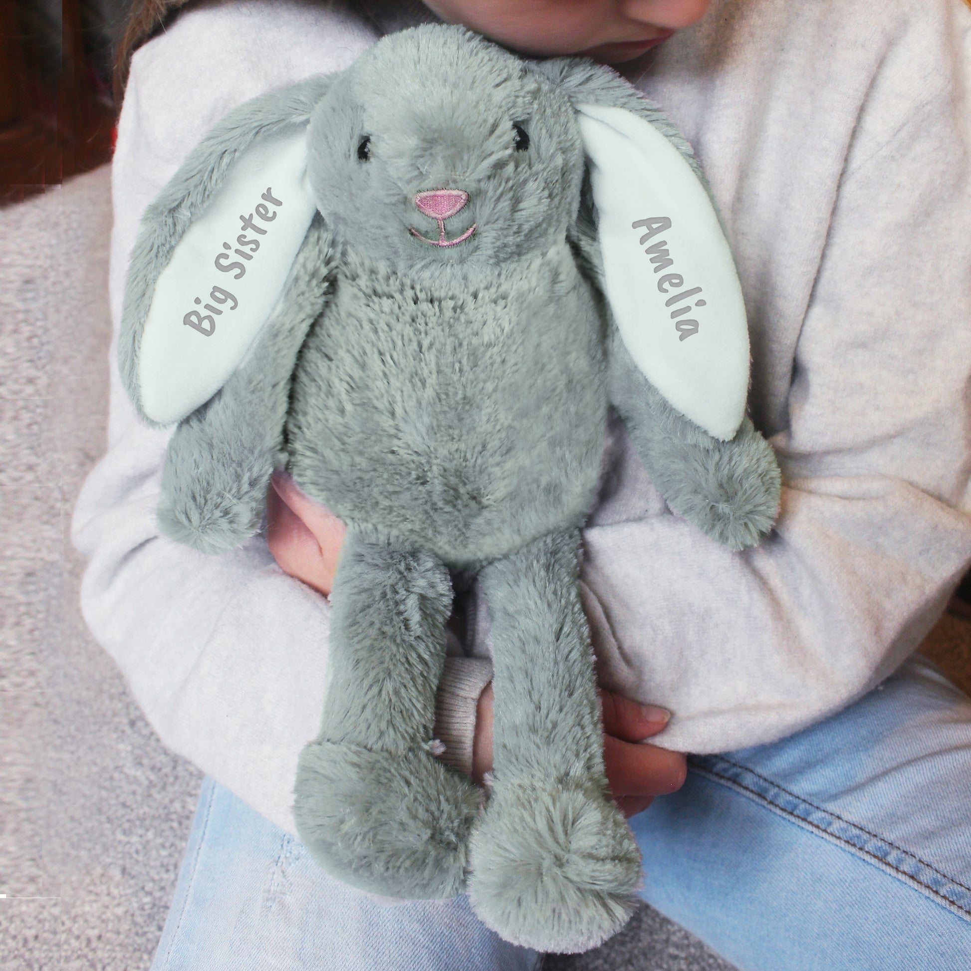 Plush bunny toy with 'Big Sister' and 'Amelia' text held by a person.