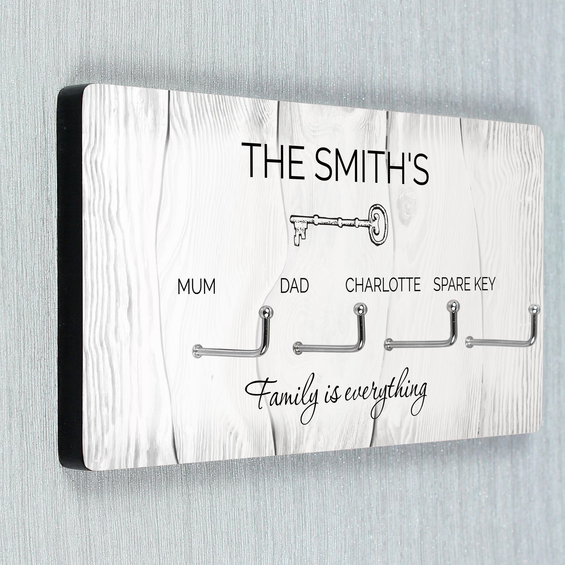 Key holder with hooks for keys, personalised with 'The Smiths' and 'Family is everything' text on a wooden pattern background.