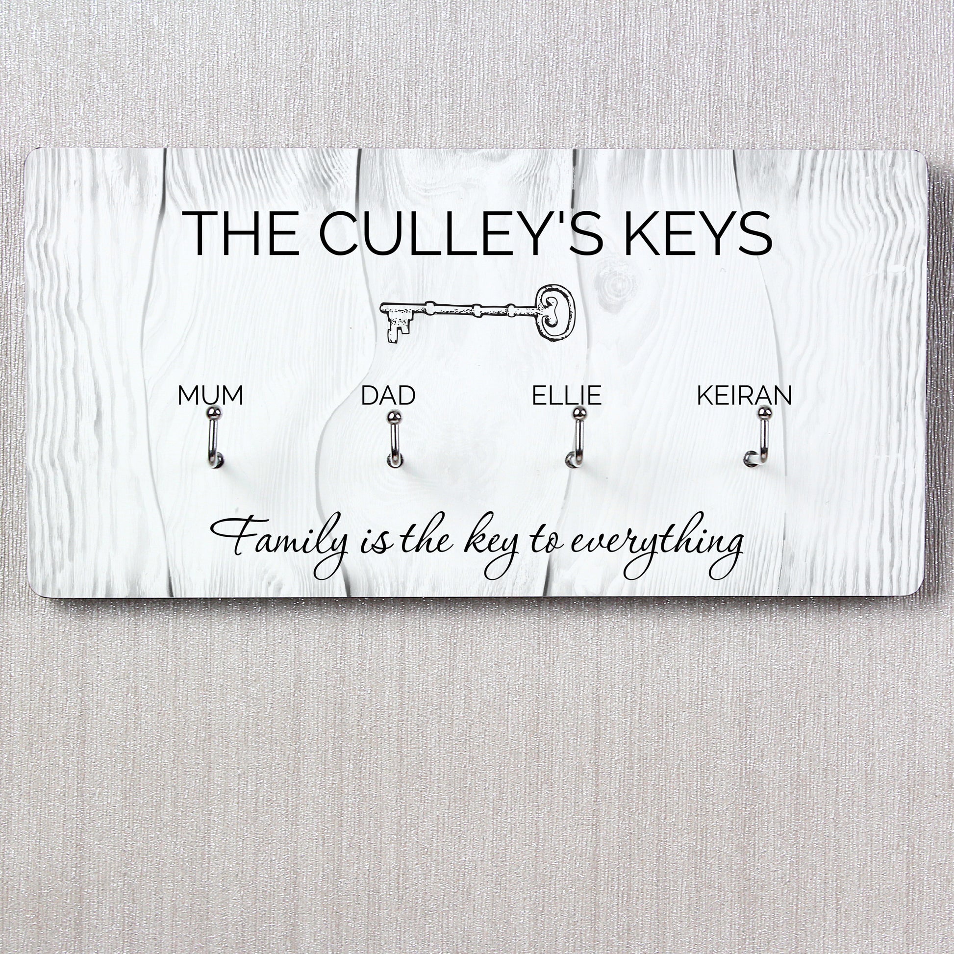 Key holder with keys for 'Mum', 'Dad', 'Ellie', and 'Keiran' on a wooden background.