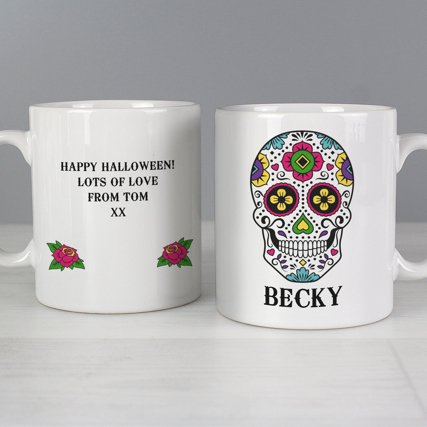 Two white mugs with personalised designs on a grey background