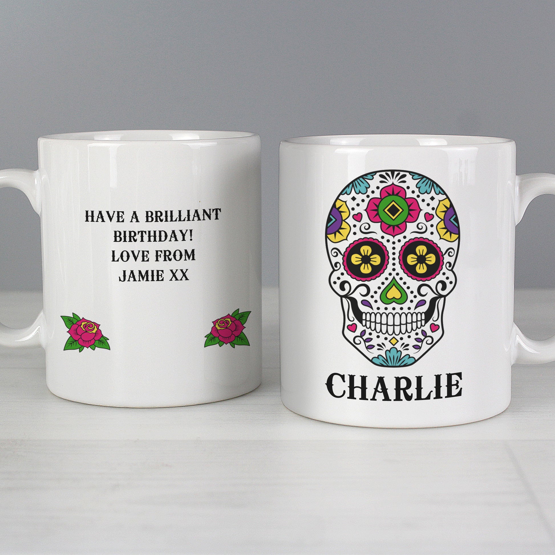 Two white mugs with personalised designs on a grey background