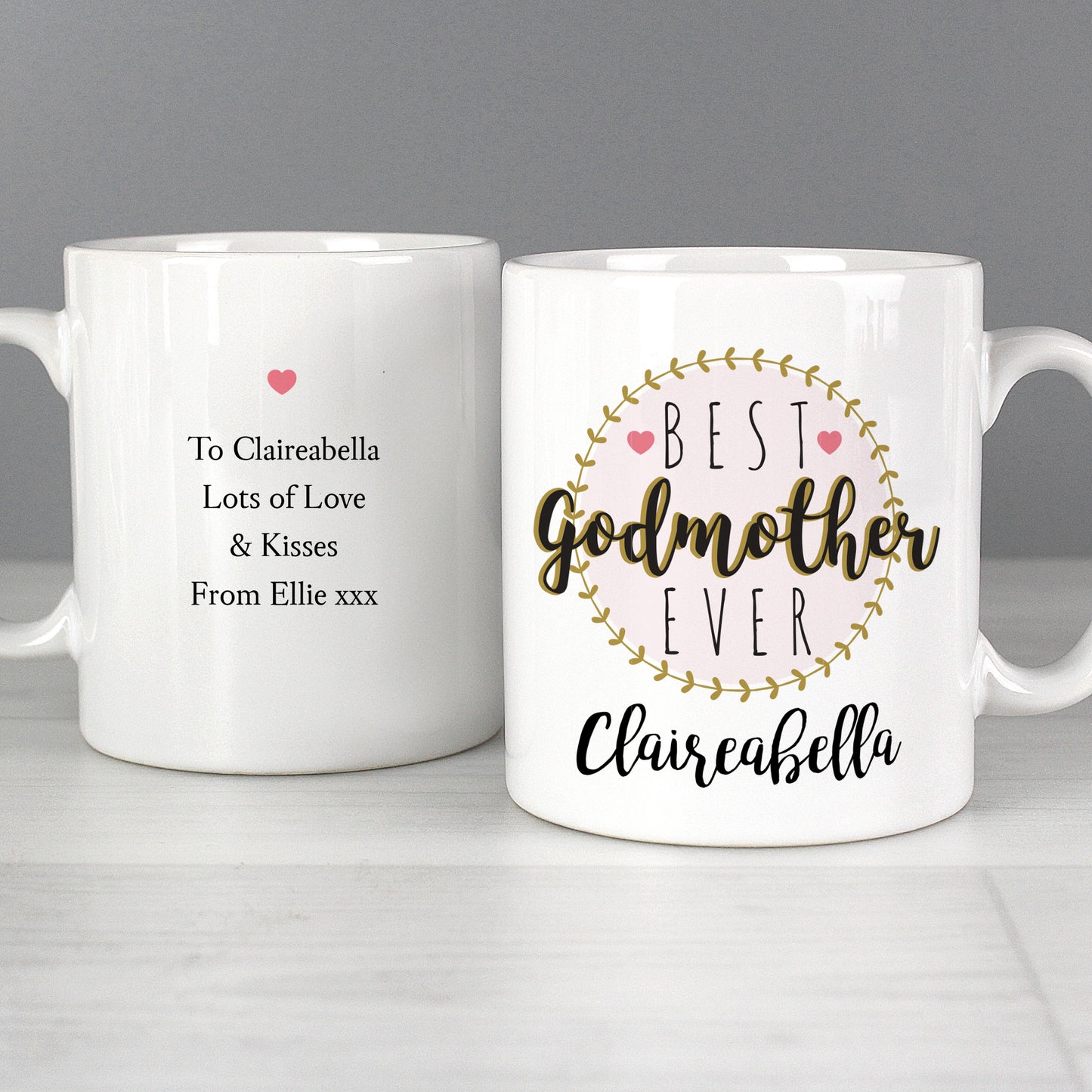 Two white mugs with personalised text on a grey background