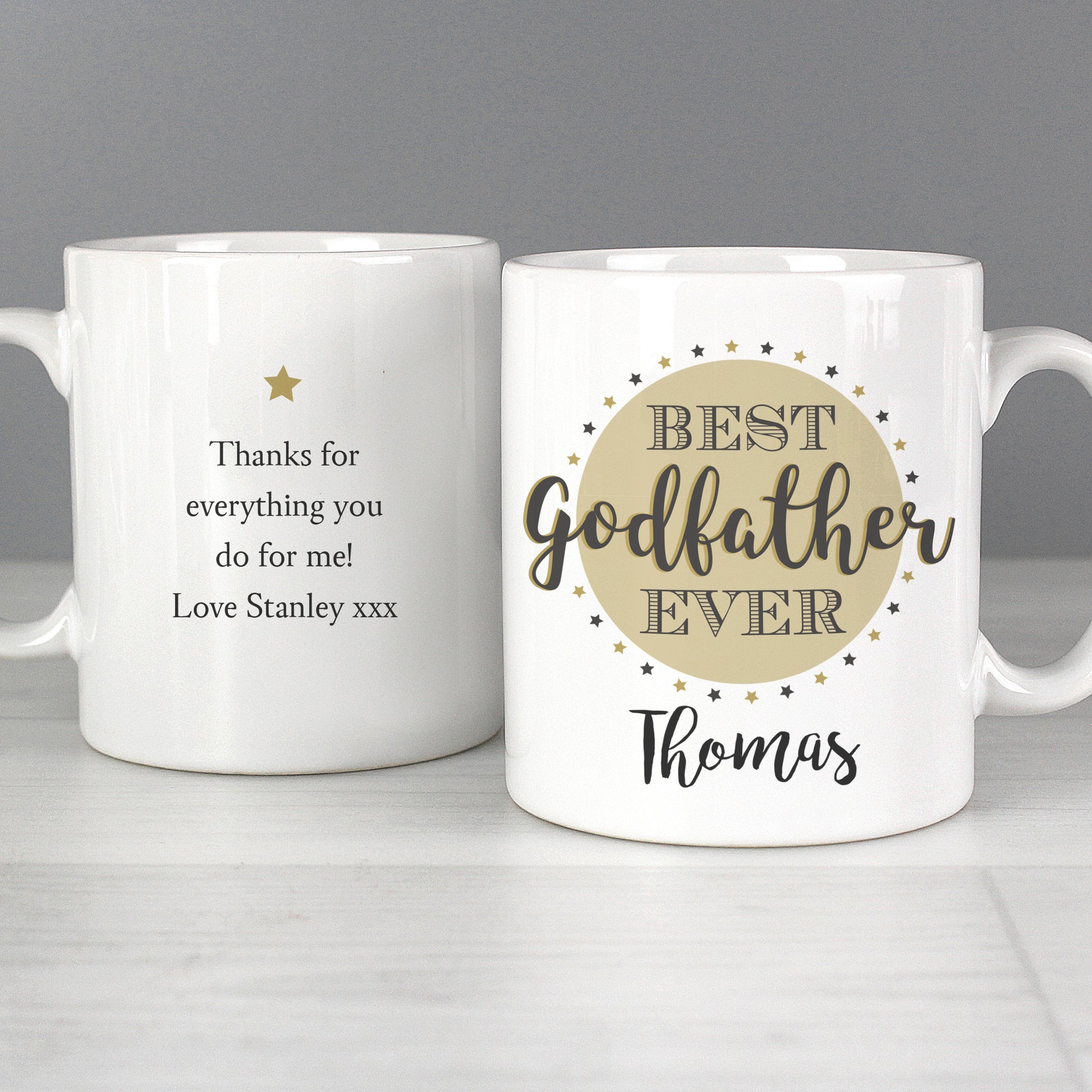 Two white mugs with personalised text on a grey background
