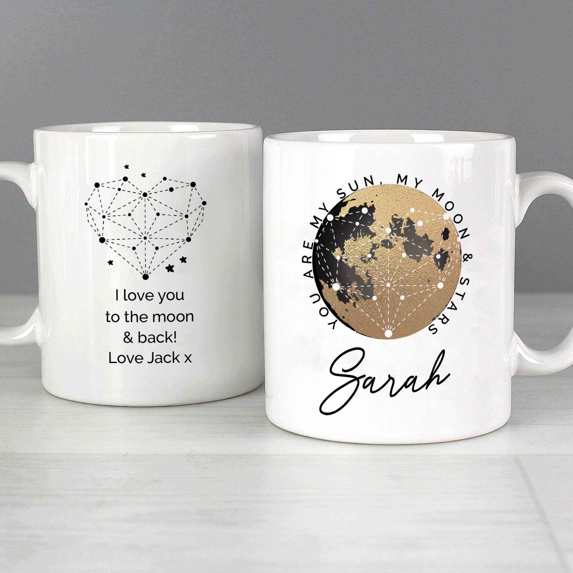 Two white mugs with star and moon designs and personalised text on a grey background.