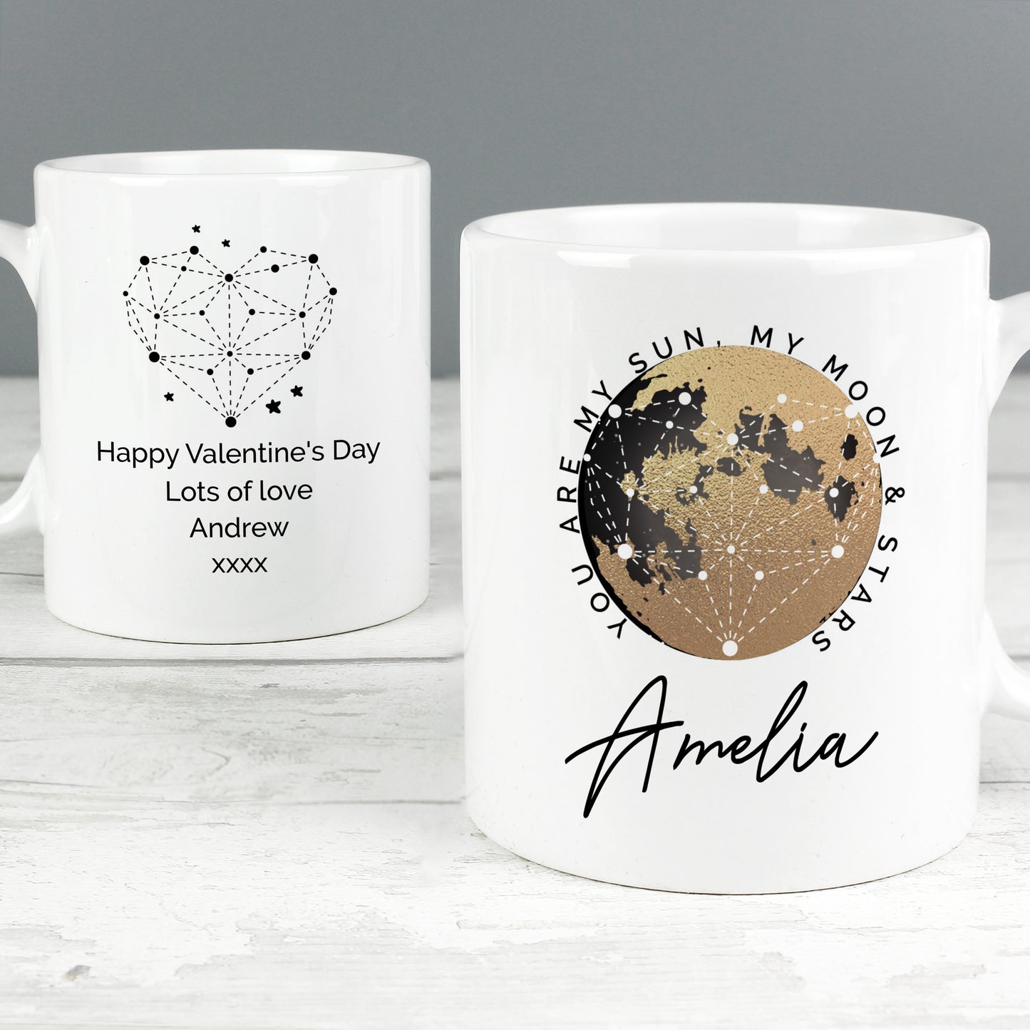 Two white mugs with romantic designs and personalised text on a grey background
