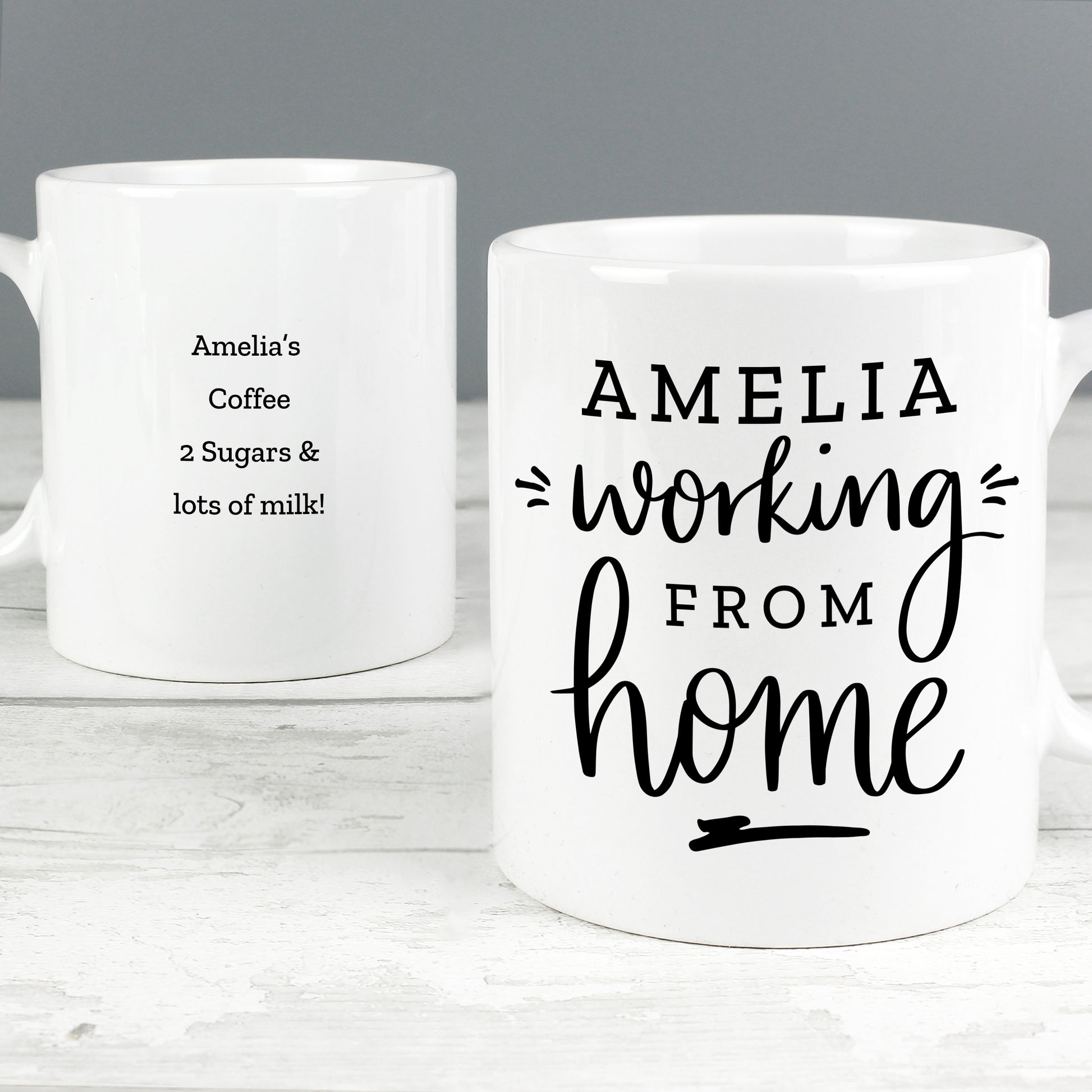 Two white mugs with personalized text on a gray background