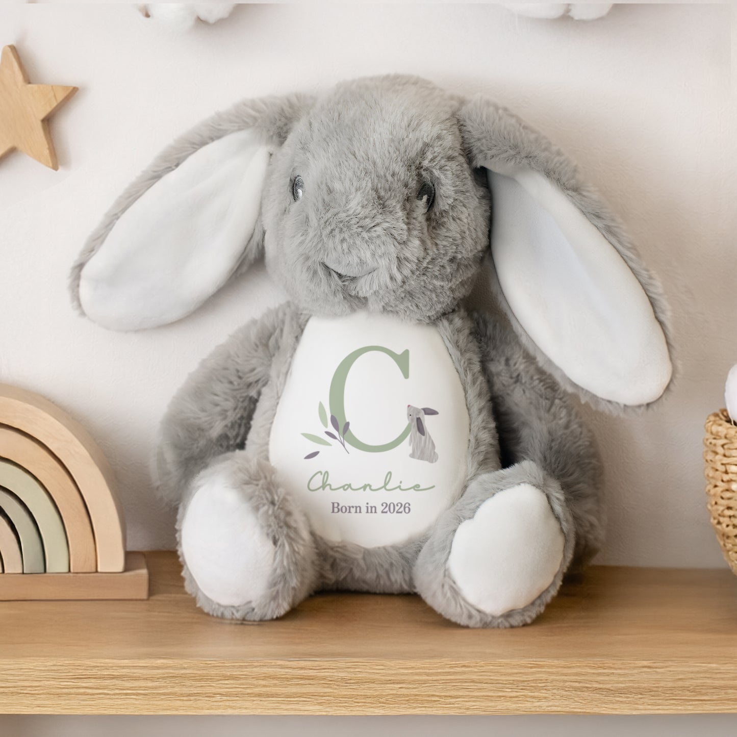 Grey personalised plush bunny with a white belly featuring text and a letter 'C' on a wooden shelf.