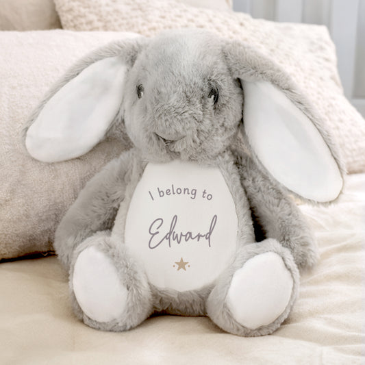 Grey plush bunny with a white belly featuring the personalised name, sitting on a soft surface.