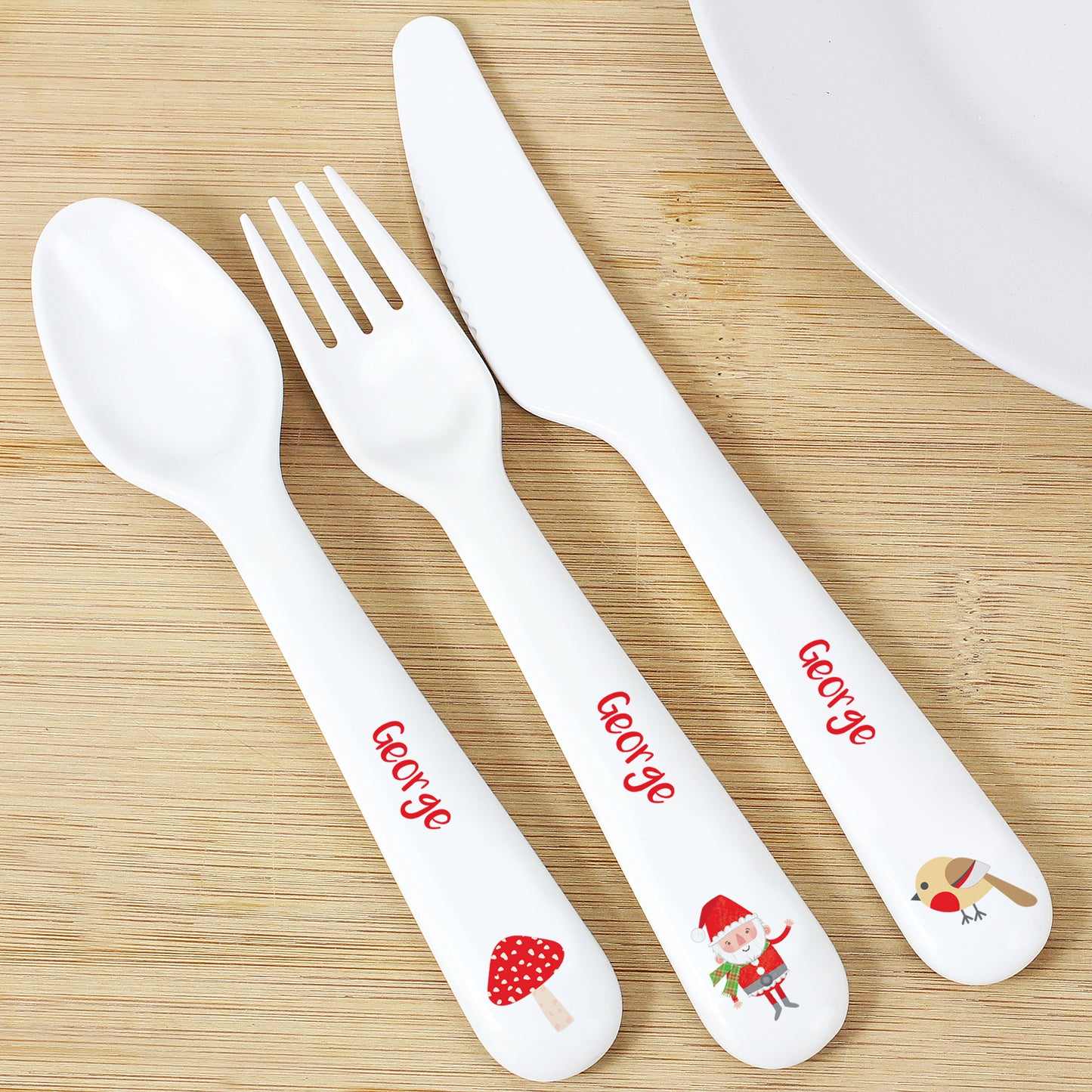 Children's cutlery set with 'George' and cartoon designs on a wooden surface