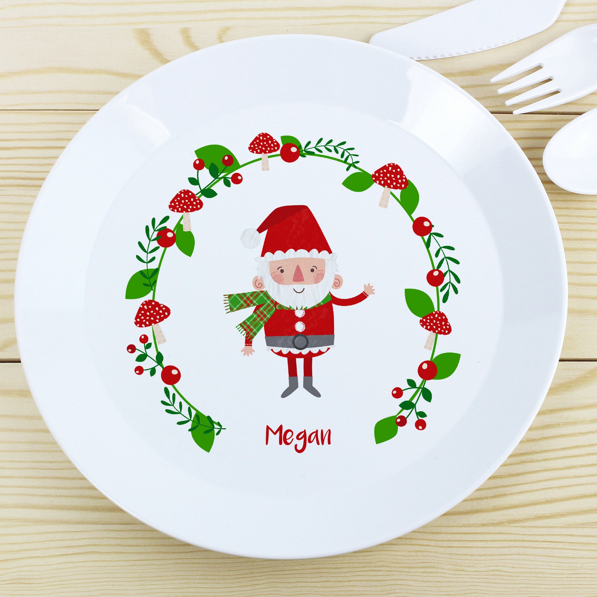Personalised White plate with a Christmas-themed design featuring a cartoon Santa Claus and holly leaves on a wooden surface.