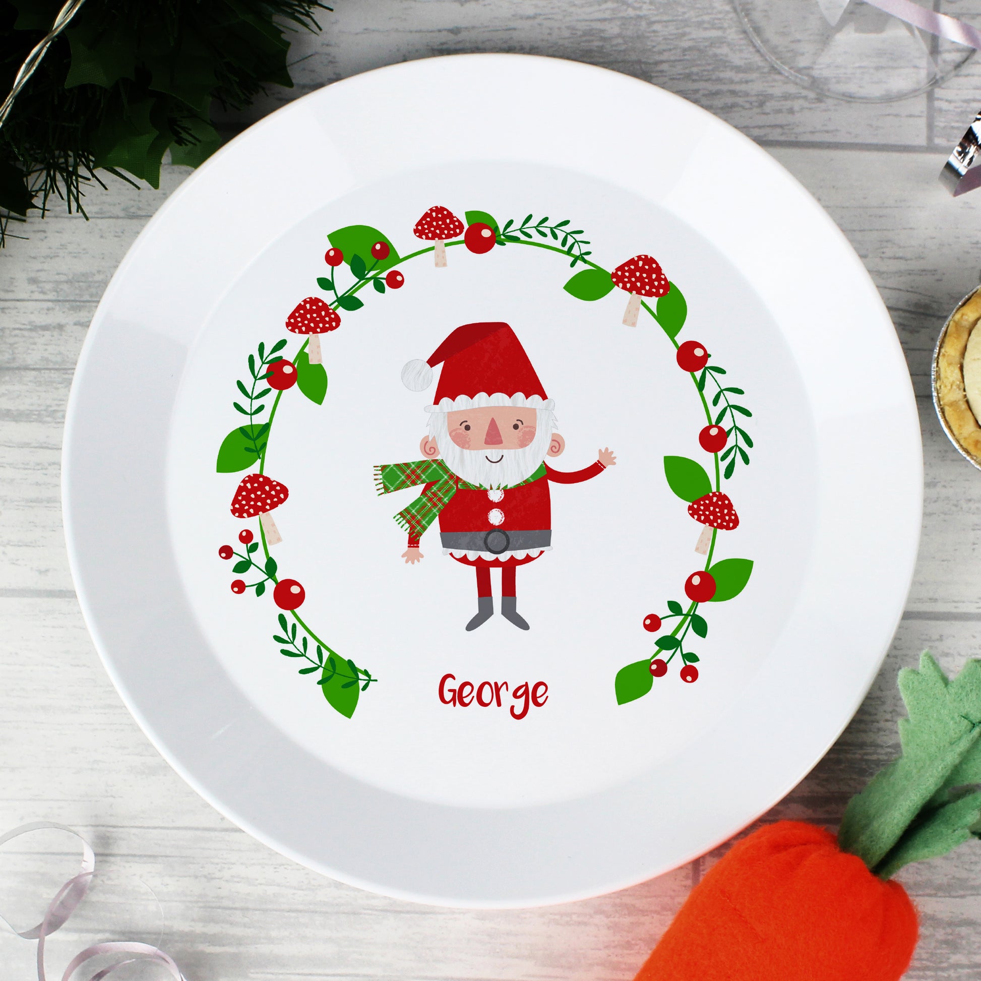 White plate with a cartoon Santa Claus design and the name 'George' on a wooden surface.