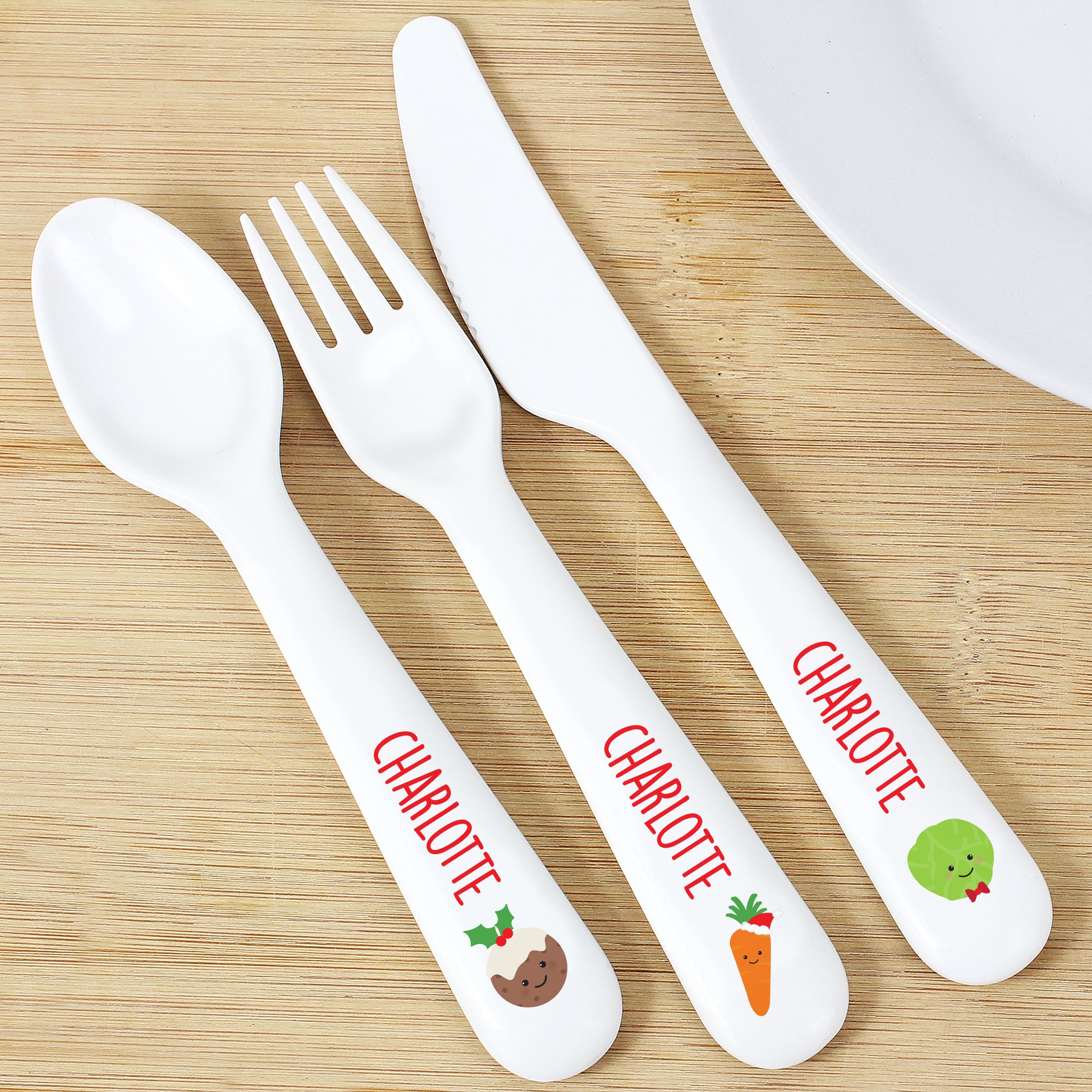 Children's cutlery set with 'Charlotte' printed on them on a wooden surface