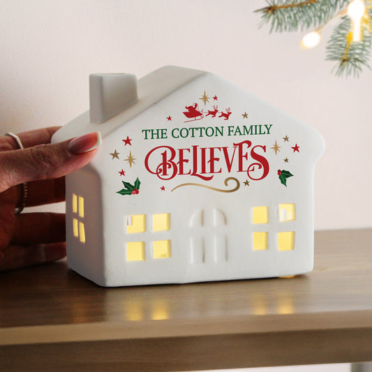 Personalised White house-shaped light with 'The Cotton Family Believes' text on a wooden surface.