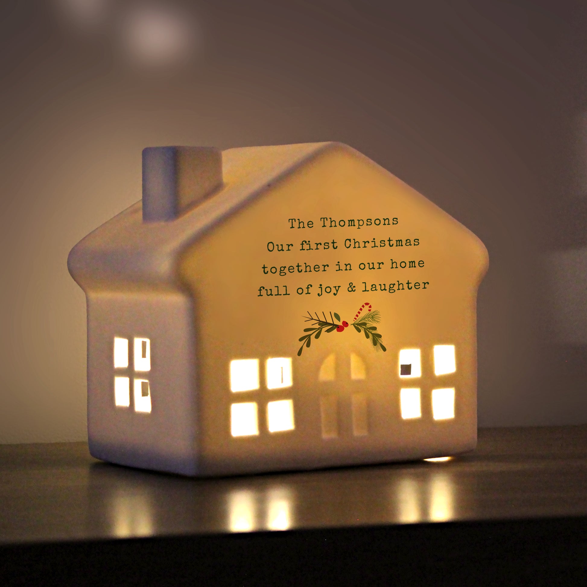 Ceramic house-shaped light with personalized message on a dark background