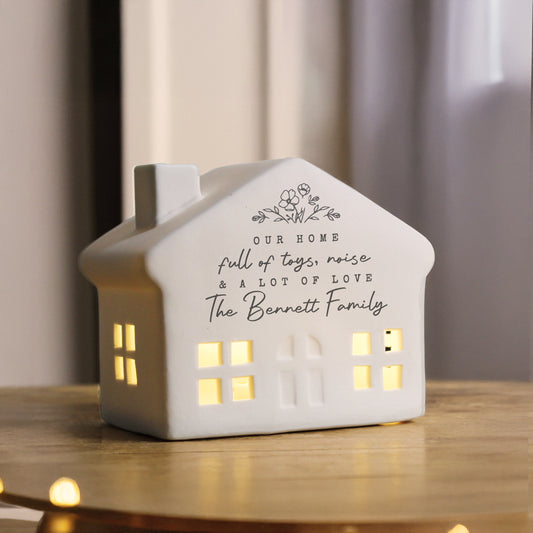 House-shaped decorative light with personalised text on a wooden surface