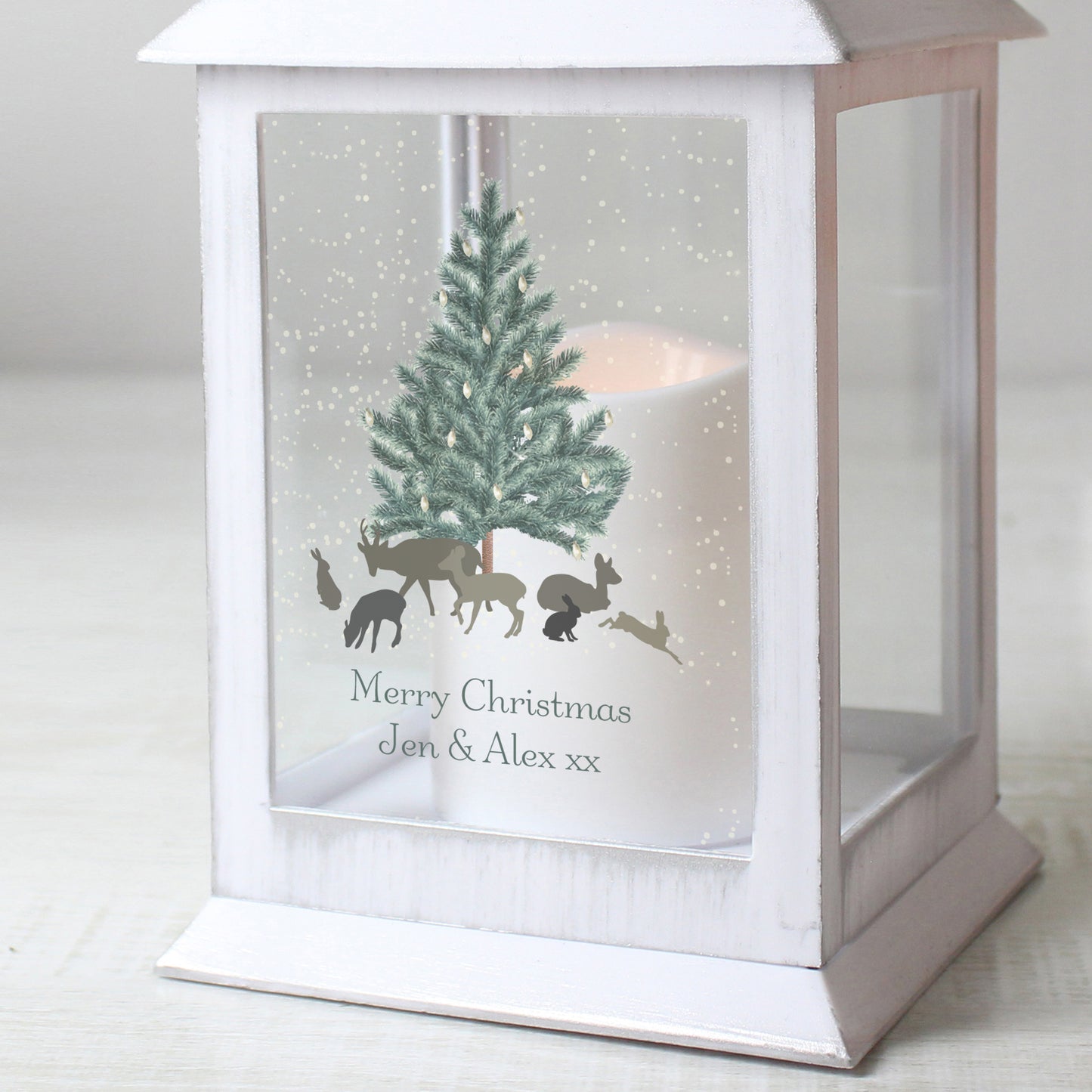 White lantern with Christmas design featuring a tree and animals on a snowy background.