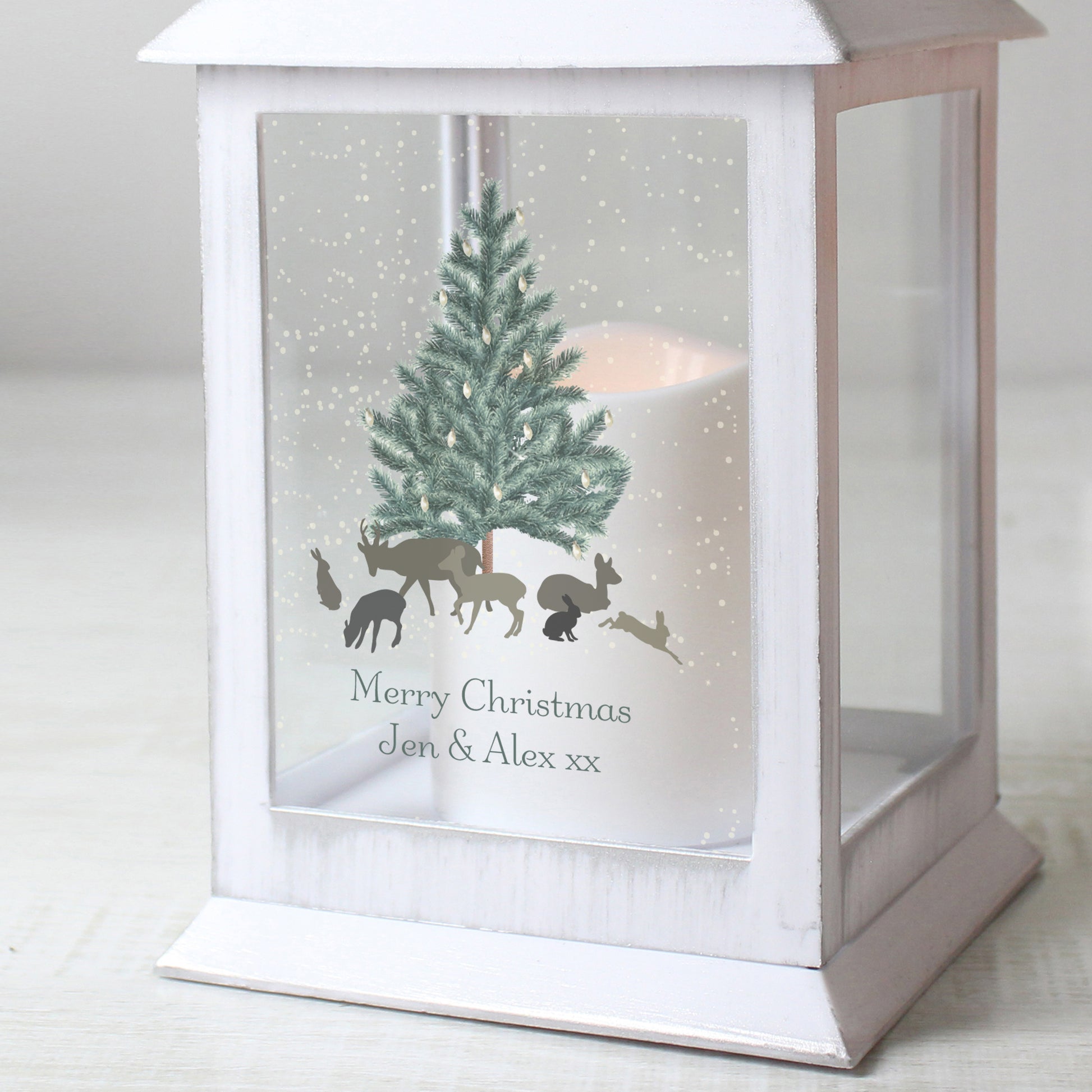 White lantern with Christmas design featuring a tree and animals on a snowy background.