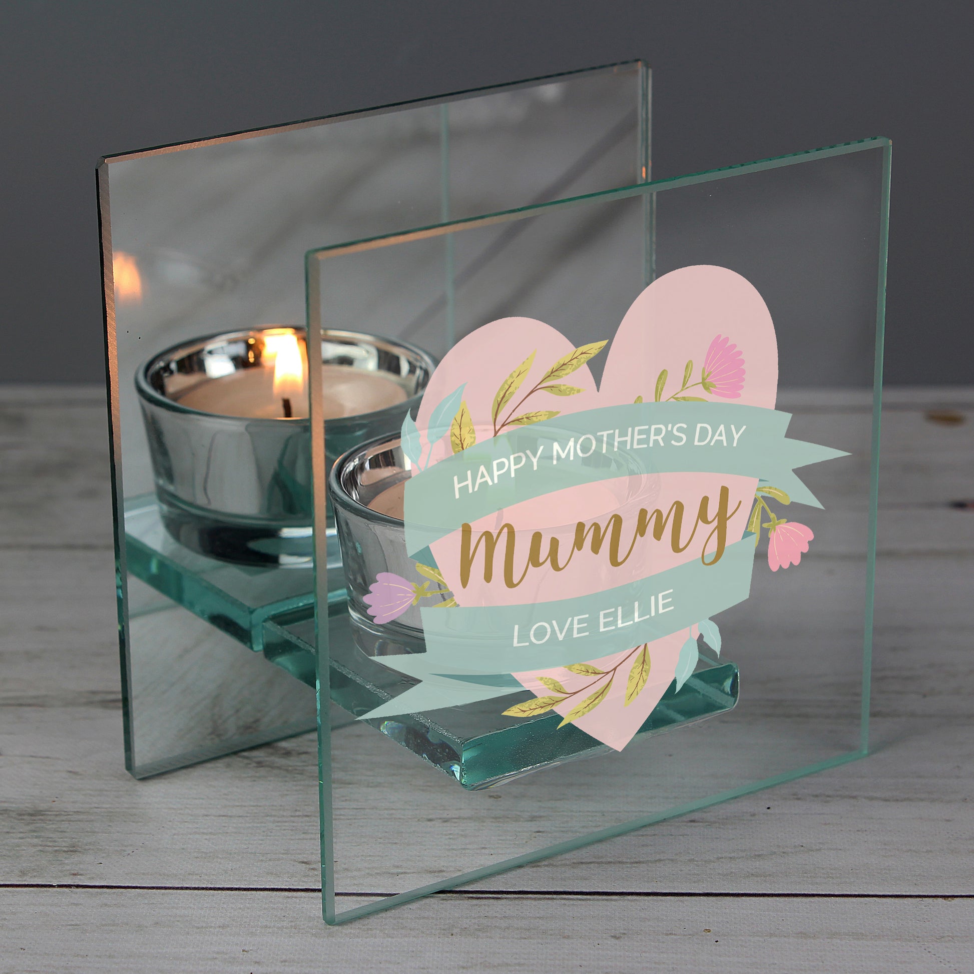 Glass holder with 'Happy Mother's Day Mummy' card and tea light candles on a wooden surface.